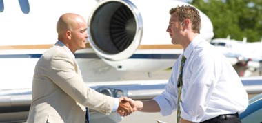 2 Businessmen shaking hands in front of an airplane